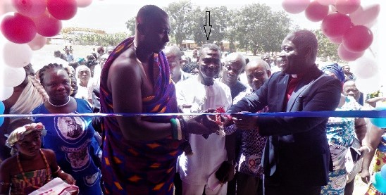 James Kwaning Sasu (arrowed) being assisted by Nana Kwaku Boateng (in cloth) to cut the tape for the inauguration of the new school block (left)